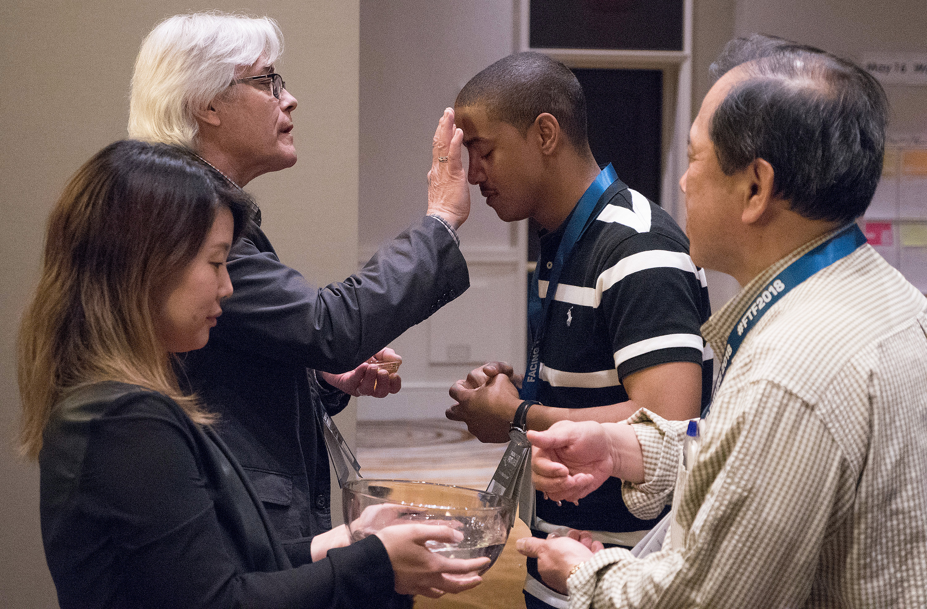The Rev. Jerome R. DeVine (left, rear) makes the sign of the cross on the Rev. Kyland Dobbins during a reaffirmation of baptism. Photo by Joey Butler, UM News.