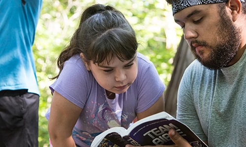 Camper Klaira Hargrove studies the Bible with counselor Emilio Almendarez during morning worship at Cedar Crest Camp in Lyles, Tennessee.