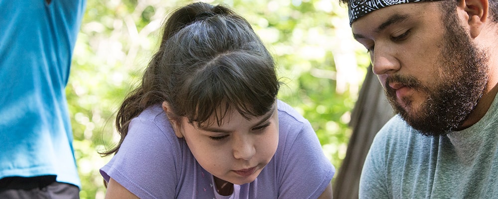 Camper Klaira Hargrove studies the Bible with counselor Emilio Almendarez during morning worship at Cedar Crest Camp in Lyles, Tennessee.