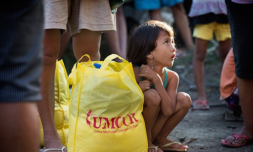 Donna-Grace Orbong, 5, sits with her family's food bag following a distribution by the United Methodist Committee on Relief for survivors of Typhoon Haiyan in Tacloban, Philippines.