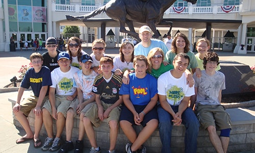 Group of students and counselor sitting on water fountain.