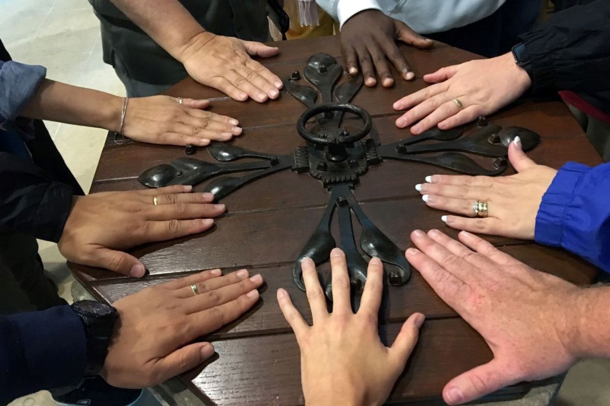 Members of the 2016 Wesley Pilgrimage in England rest their hands on the Baptismal font at St. Andrew's church in Epworth, England where John Wesley was baptized. Photo by the Rev. Anita Mays (Permission granted by the Rev. Anita Mays of Midlothian, Virgini with photo credit.