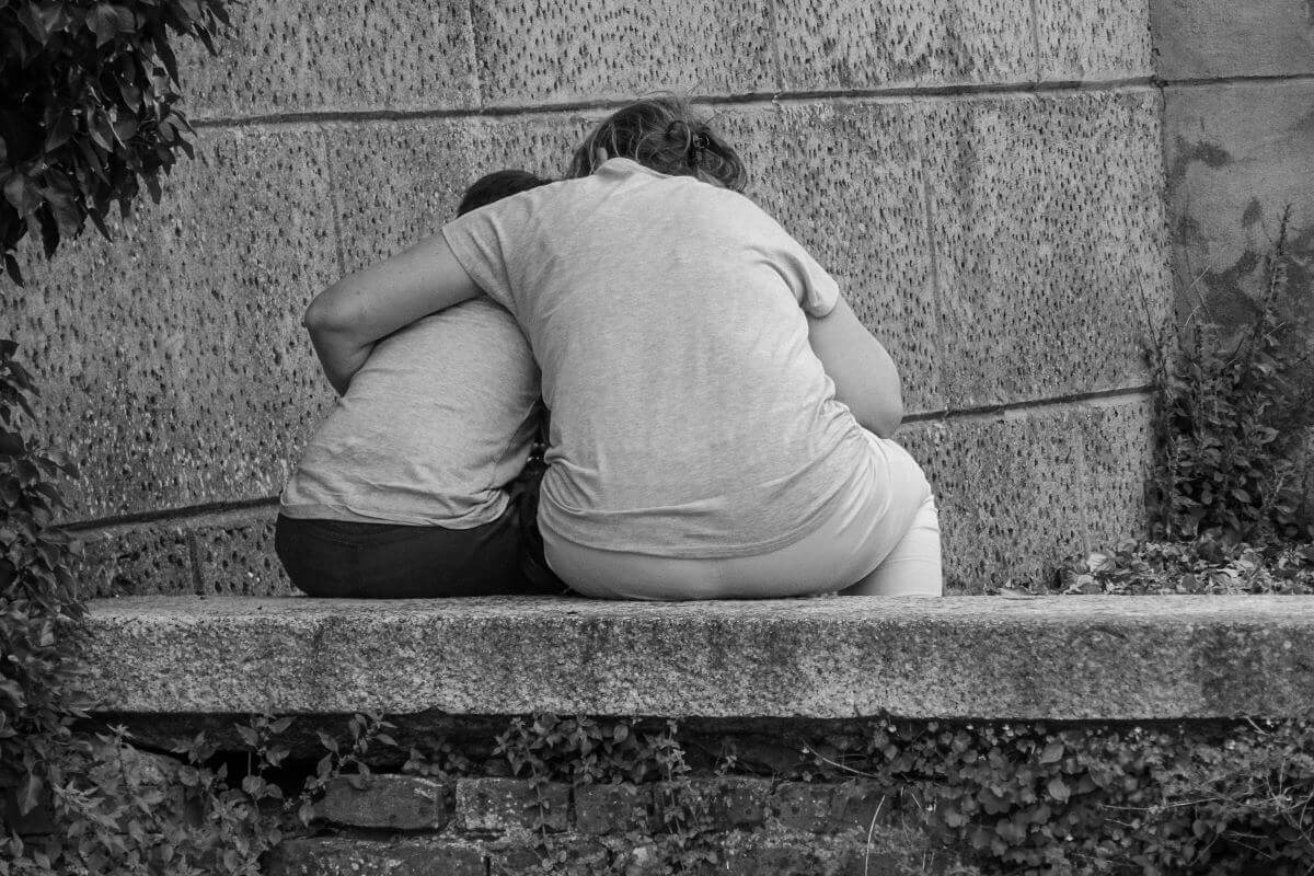 Adulto abraza a un niño para darle consuelo.