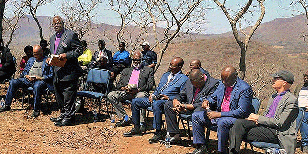 Retired Bishop David Yemba of Central Congo (standing) leads fellow bishops in a time of prayer and reflection on a mountain overlooking Africa University in Mutare, Zimbabwe. The Africa Colleges of Bishops held its annual retreat Sept. 2-5 at the United Methodist university. Photo by Eveline Chikwanah, UM News.