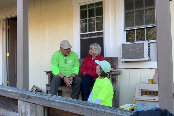 Al Tompkins and Carolyn Koontz talk with Anita McKinney on the porch of her home in Newland, N.C. Screengrab by Lilla Marigza, UM News.