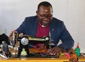 Bishop João Filimone Sambo displays his own sewing skills at the launch of the Cutting, Sewing and Cooking Project in Bela-Vista, Mozambique.